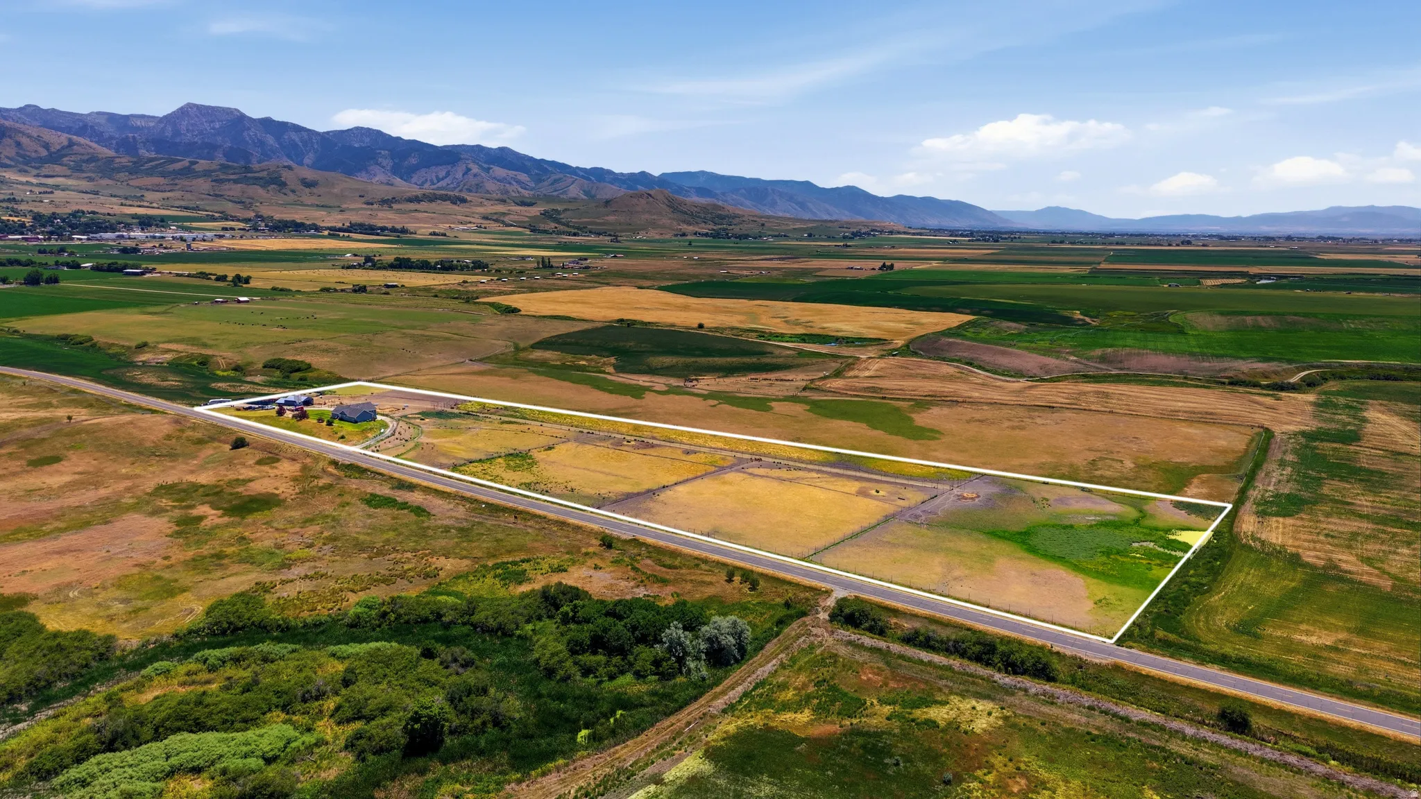 Expansive parcel featuring a single-family residence, multiple outbuildings, and direct road frontage