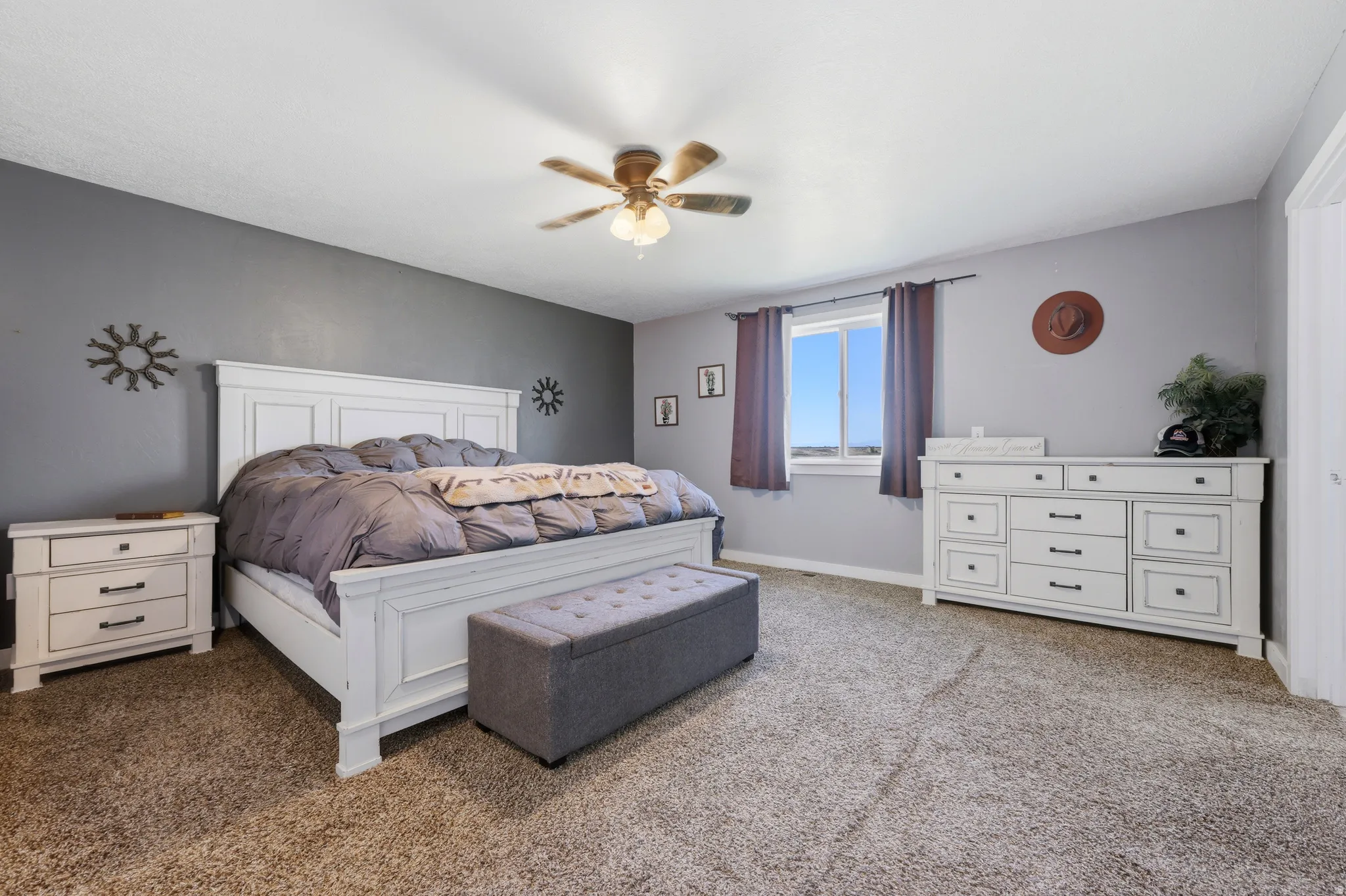 Spacious bedroom featuring neutral carpeting, a dual-pane window, and a ceiling fan with integrated lighting