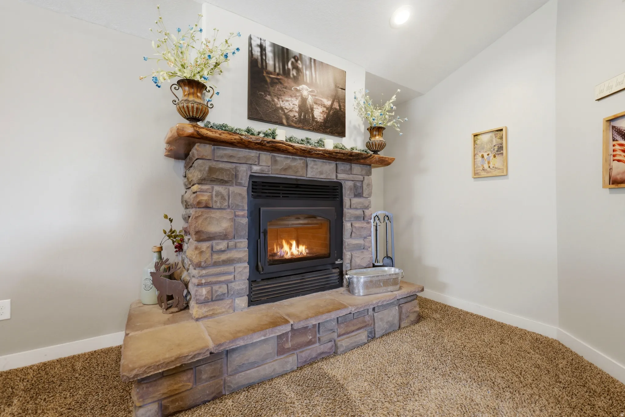 Stone-clad fireplace featuring a wood-finish mantel and a raised stone hearth