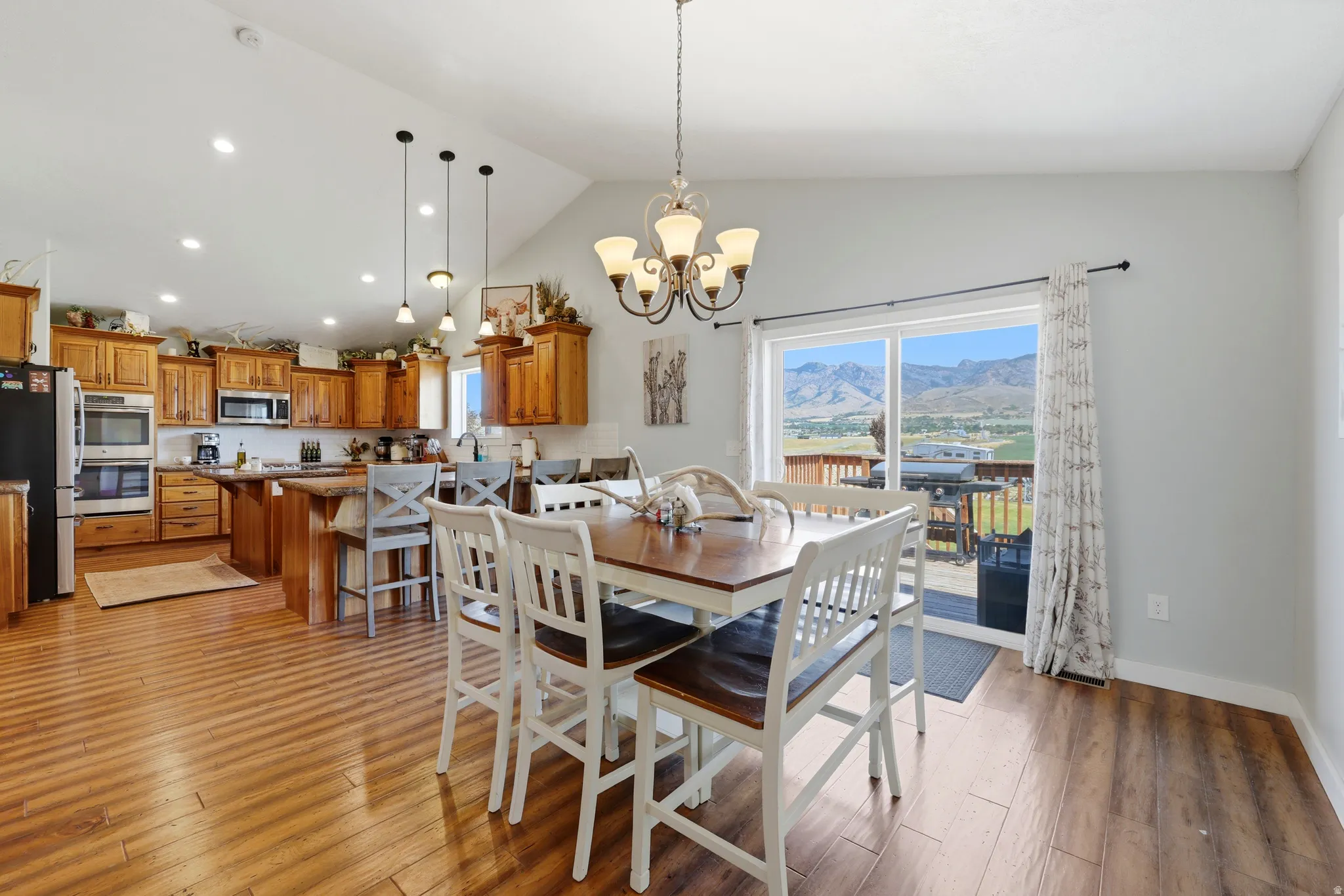 Open-concept living space featuring wood-finish flooring, vaulted ceilings, and a kitchen with warm wood cabinetry and a central island