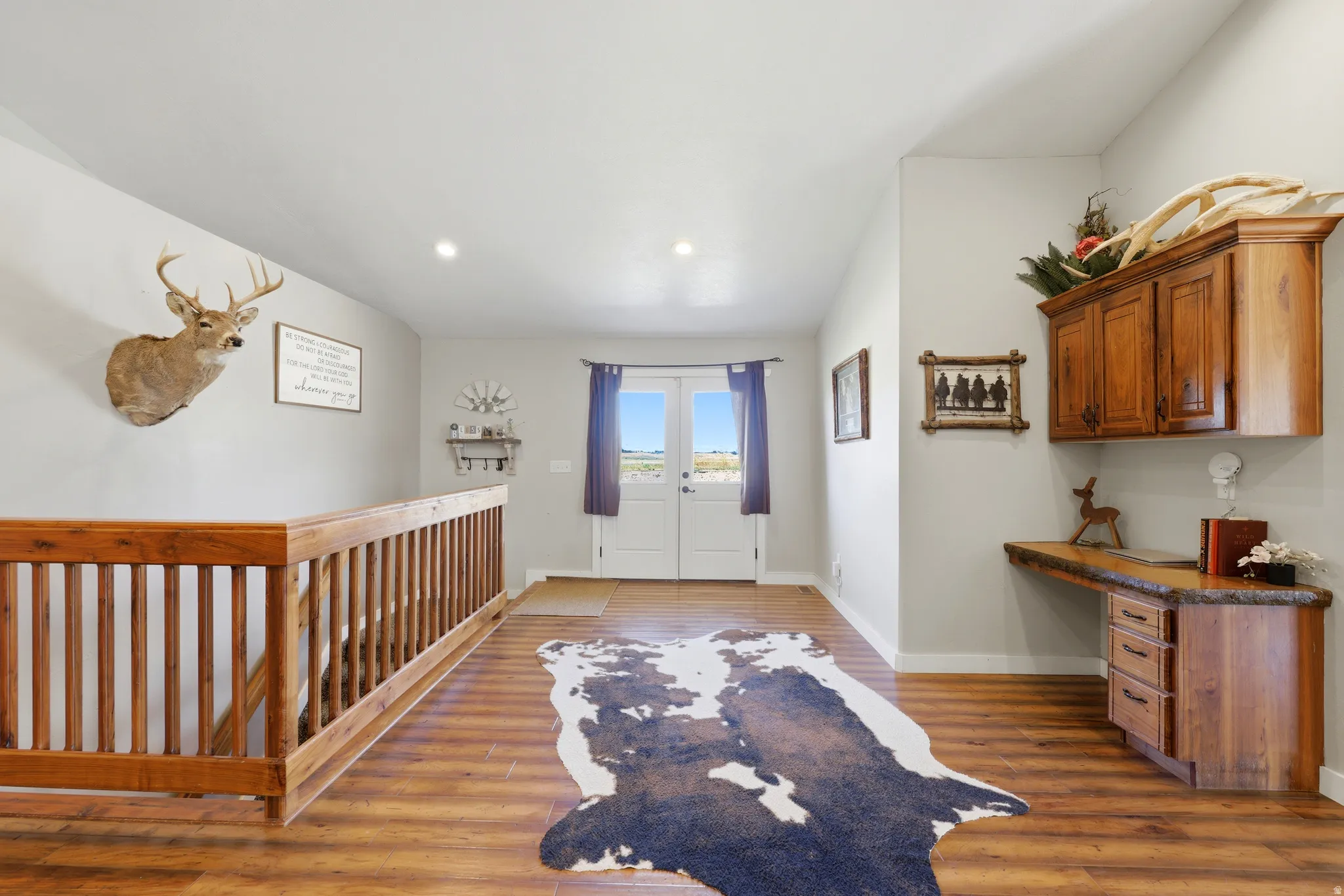 Foyer featuring wood-finish flooring, a wood-toned stair railing, white walls, and recessed lighting