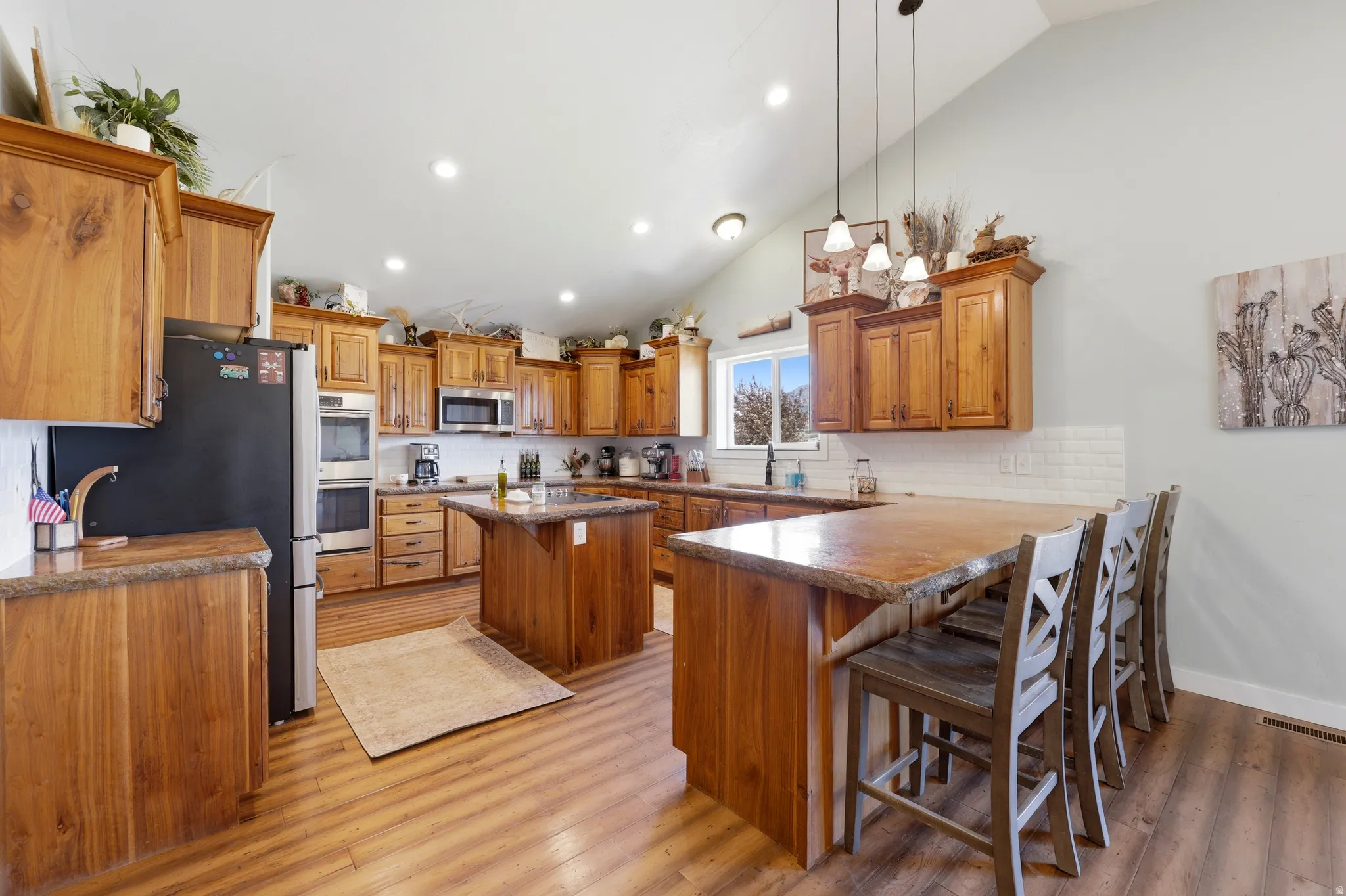 Spacious kitchen featuring extensive wood cabinetry, a central island with a stone countertop, and a breakfast bar