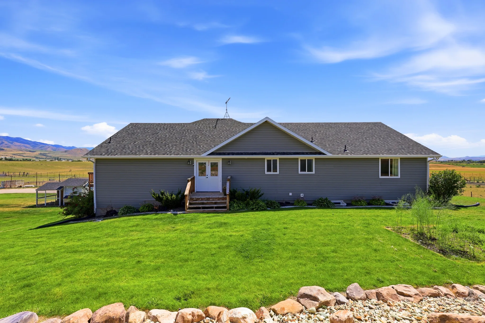 Rear exterior featuring gray siding, a dark shingle roof, and white-framed windows