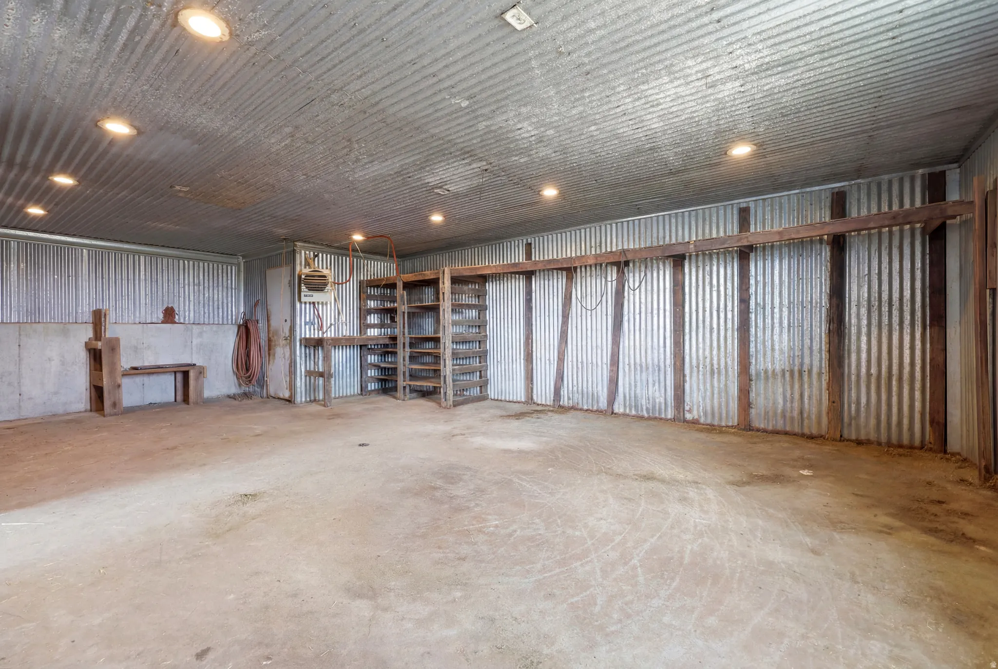 Large concrete-floored interior space with corrugated metal walls and ceiling