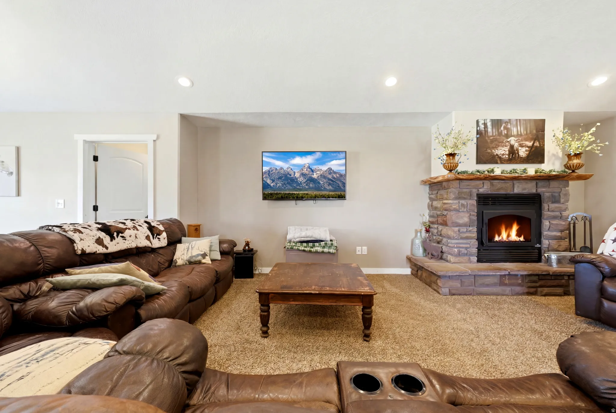 Stone-clad corner fireplace with a rustic wood mantel