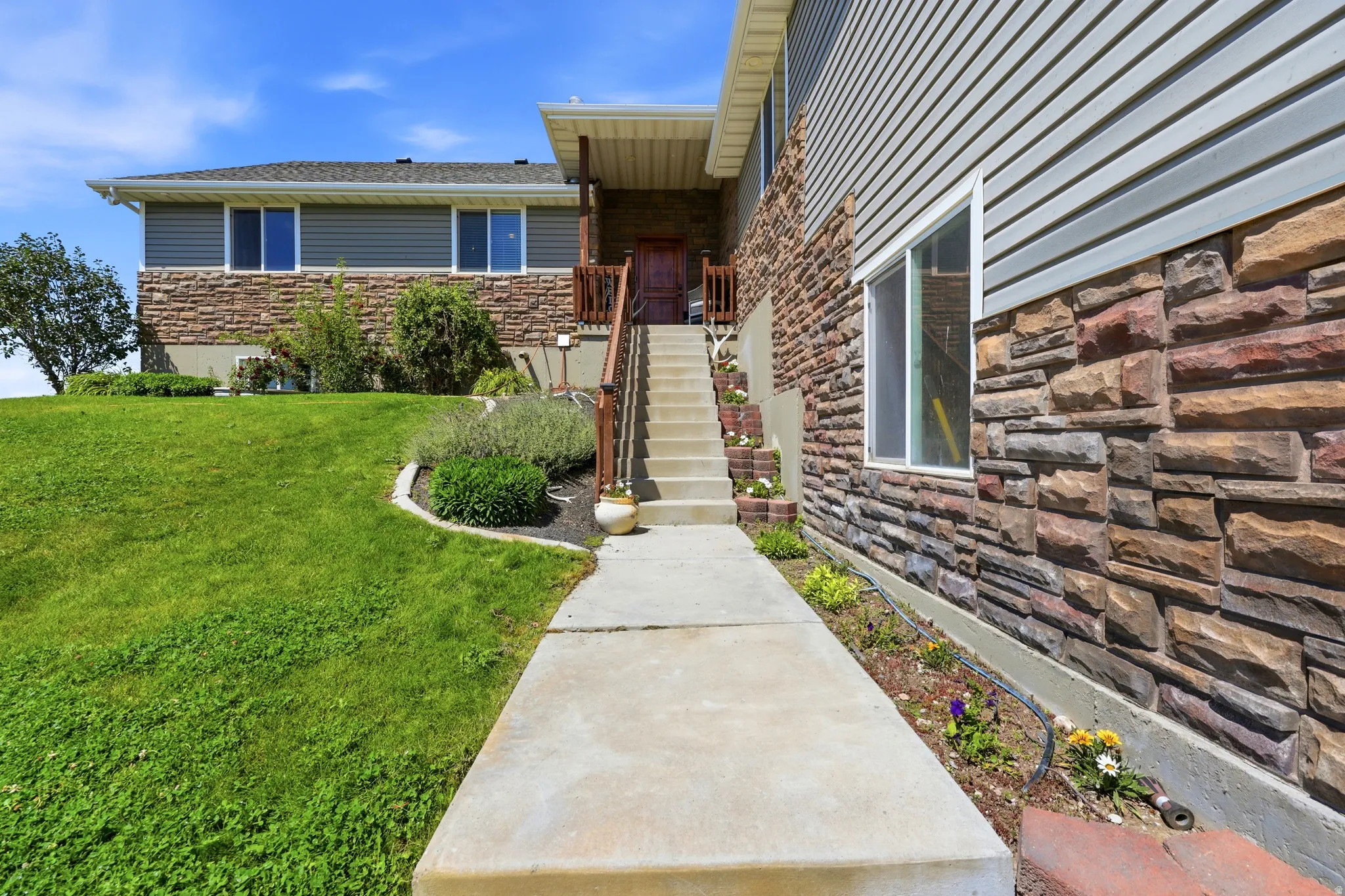 Split-level exterior featuring horizontal siding and stacked stone accents