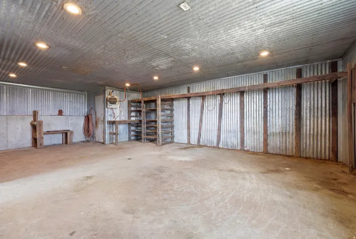 Large concrete-floored interior space with corrugated metal walls and ceiling