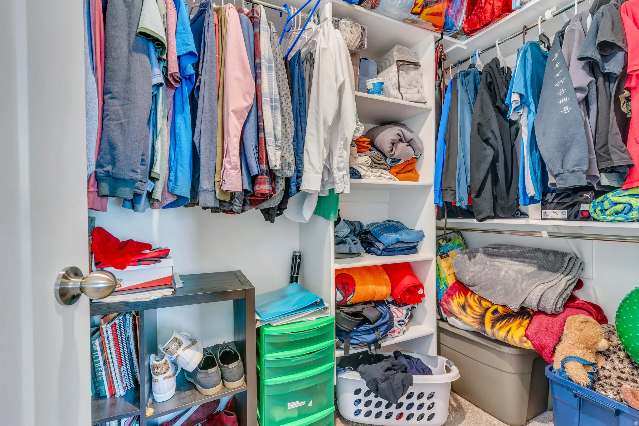 Walk-in closet featuring white built-in shelving, multiple hanging rods, and carpet flooring