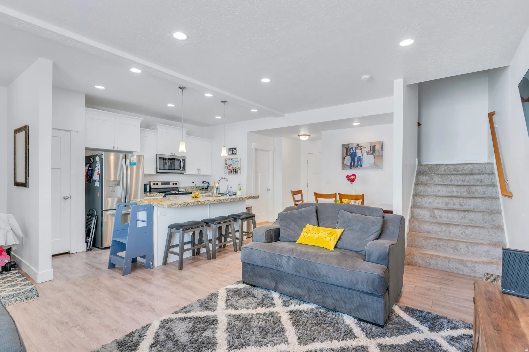 Open-concept living area featuring light wood-finish flooring, recessed lighting, and a neutral color palette