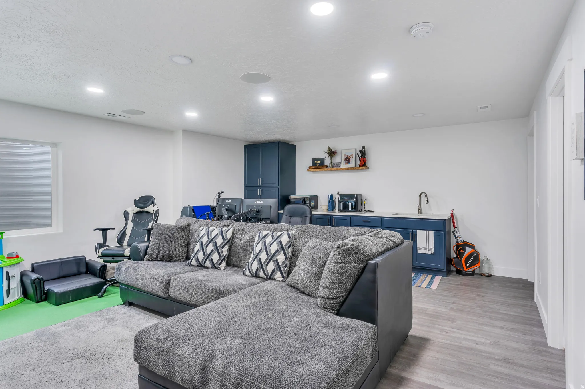 Expansive room featuring recessed lighting and a wet bar with dark blue cabinetry