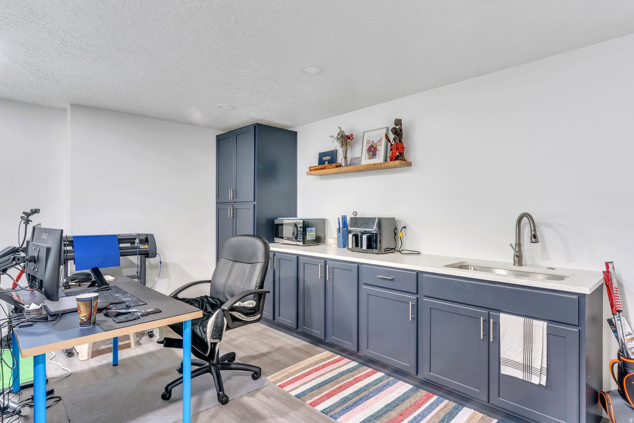 Integrated workstation featuring a built-in sink, dark cabinetry, light-toned countertop, and wood-finish flooring