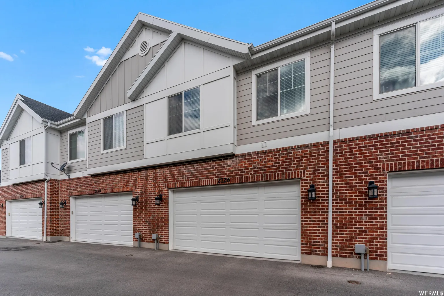 Multi-level exterior featuring brick and horizontal siding, with multiple garage entrances