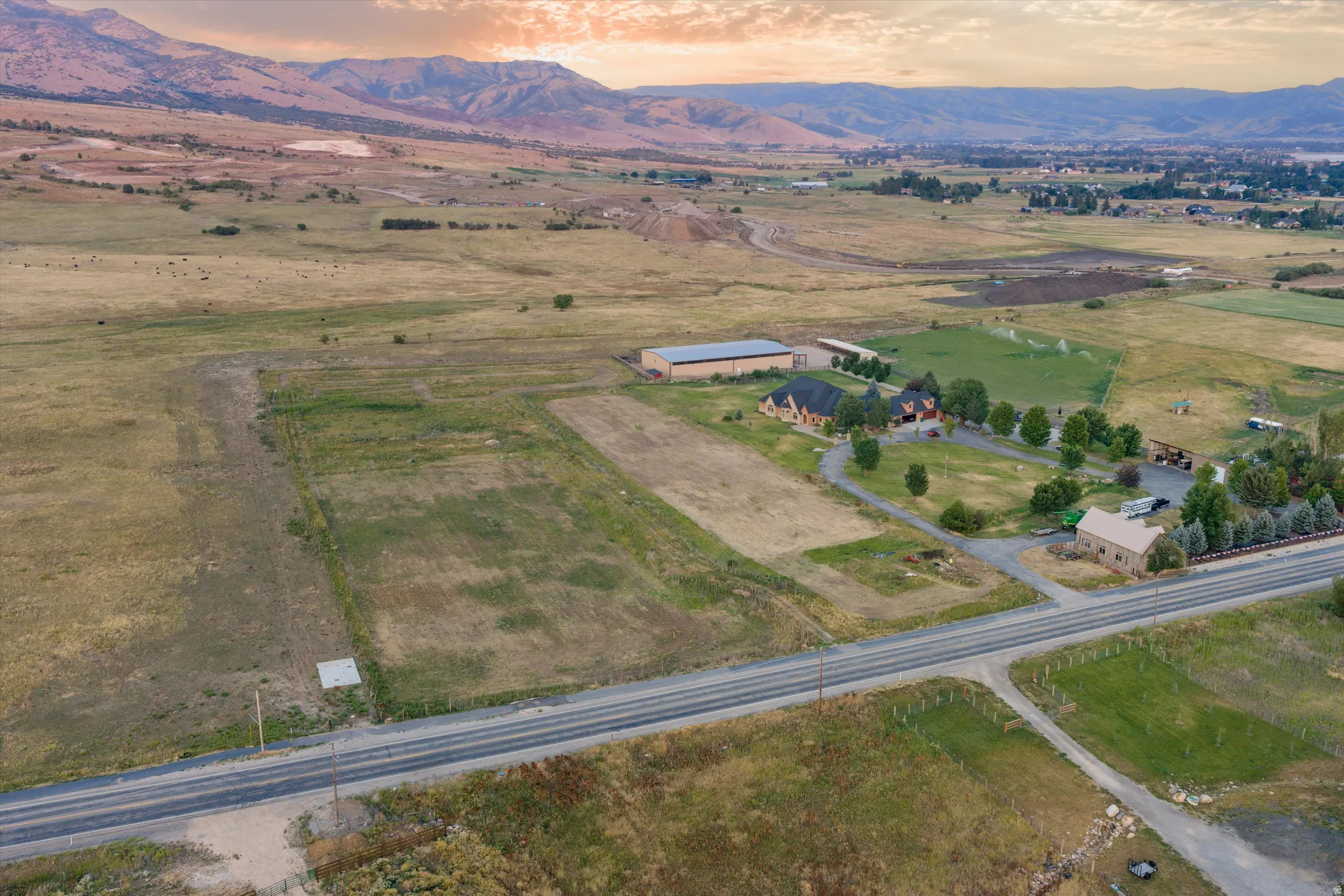 Expansive rural landscape featuring multiple structures, cultivated fields, and a paved road