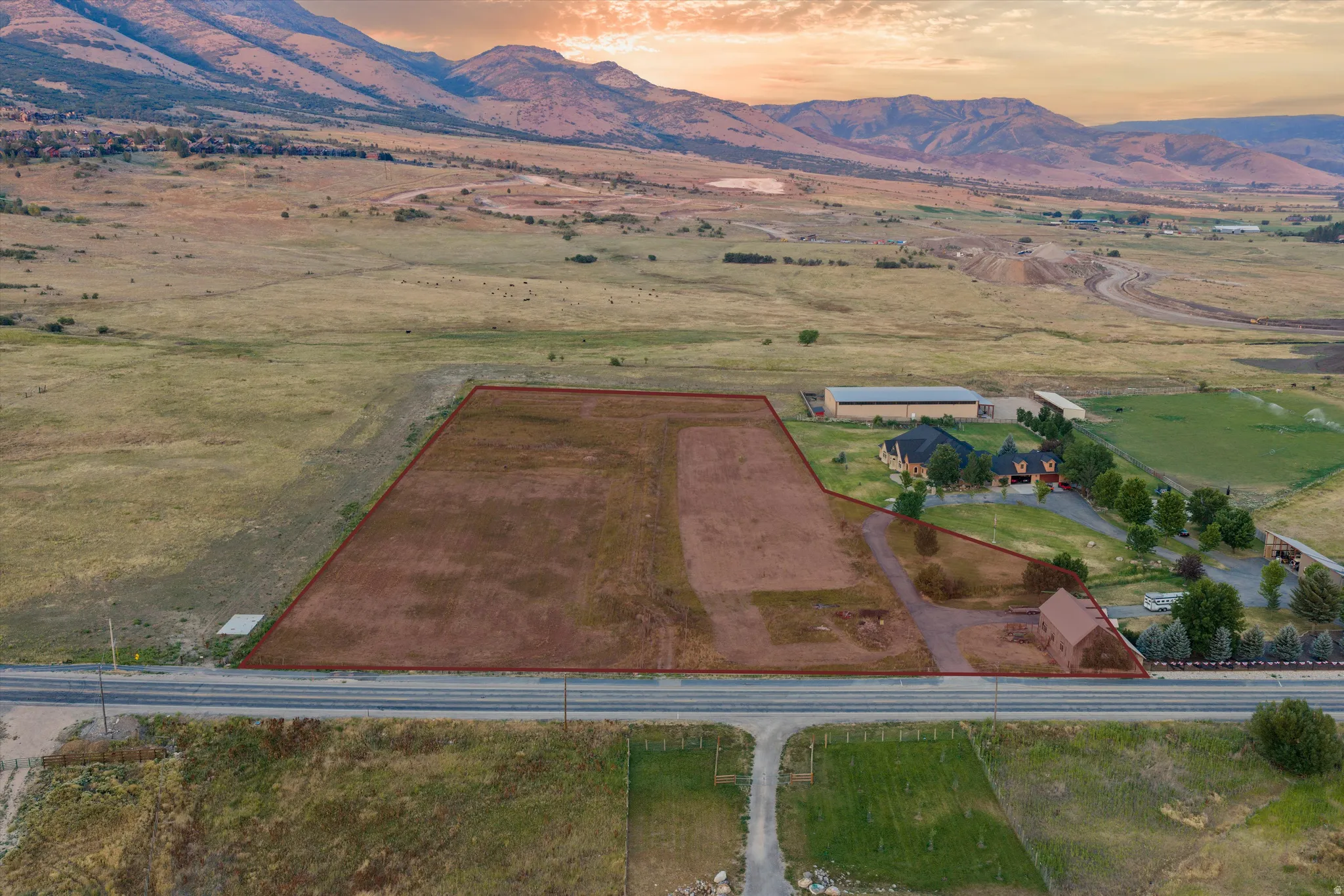 Expansive acreage featuring a substantial cleared lot, paved road frontage, and mountainous terrain in the background