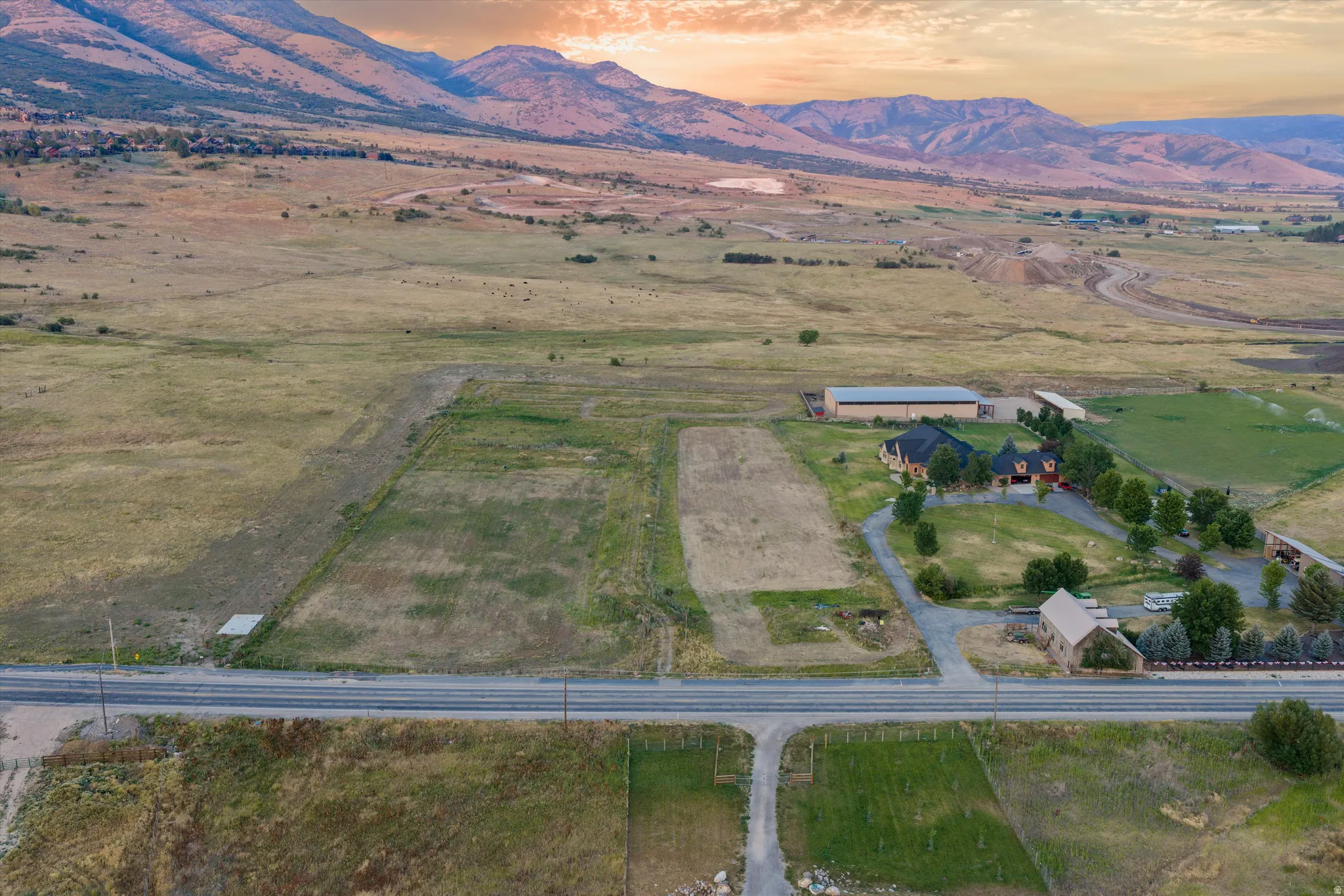 Expansive property featuring a paved road frontage, extensive open land, and a distant mountainous backdrop
