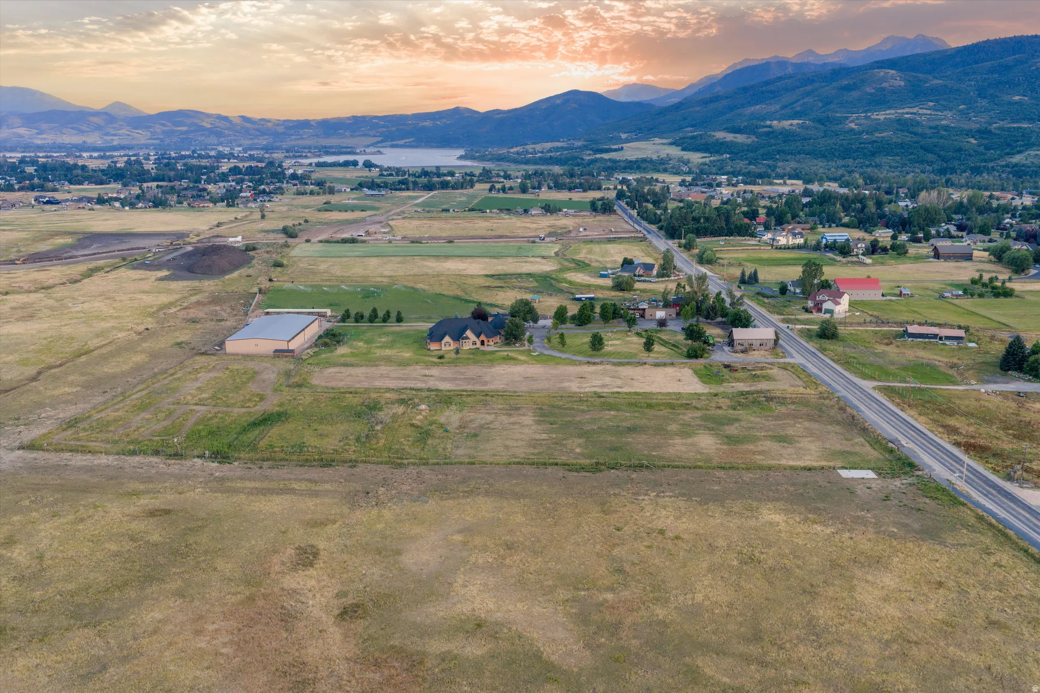 Expansive rural property featuring a large residence with a circular driveway, substantial outbuilding, and significant undeveloped land