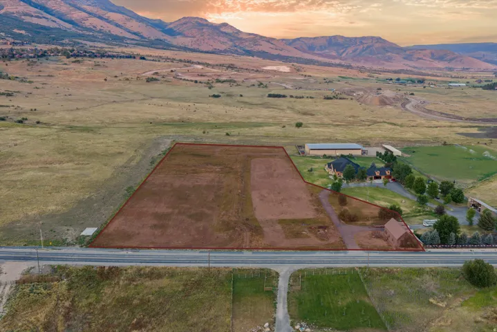 Expansive acreage featuring a substantial cleared lot, paved road frontage, and mountainous terrain in the background