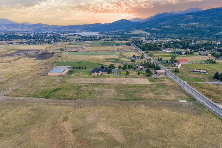 Expansive rural property featuring a large residence with a circular driveway, substantial outbuilding, and significant undeveloped land