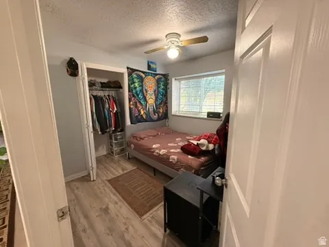 Room featuring wood-finish flooring, a window with blinds, and a ceiling fan with integrated lighting