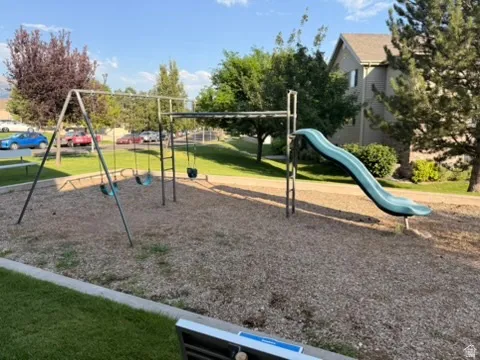 Community playground featuring swings, a slide, and monkey bars, set on wood chip surfacing
