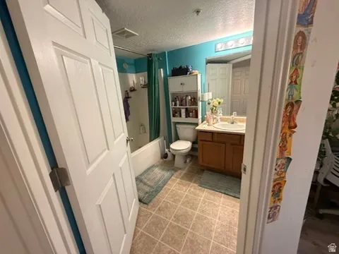 Bathroom featuring a single vanity with wood-finish cabinetry, a built-in bathtub with shower, and tile flooring