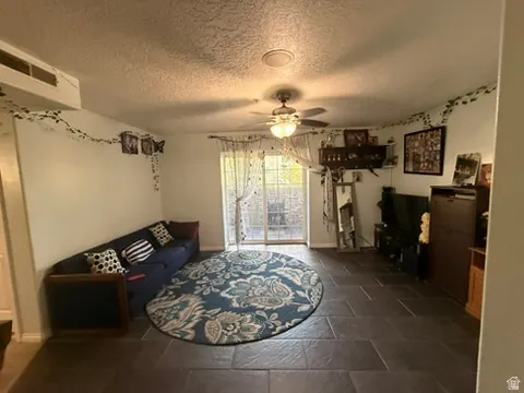 Living area with dark tile flooring and a ceiling fan light fixture