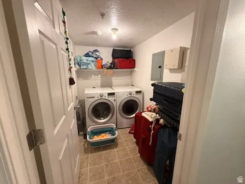 Dedicated laundry area featuring dual front-loading machines, overhead shelving, and neutral-toned tile flooring