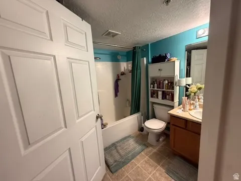 Bathroom featuring a tub/shower combination, tile flooring, a single-sink vanity with a wood-finish cabinet, and a wall-mounted medicine cabinet