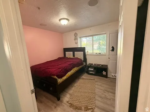 Room featuring wood-finish flooring, a contemporary ceiling light fixture, and a window with blinds
