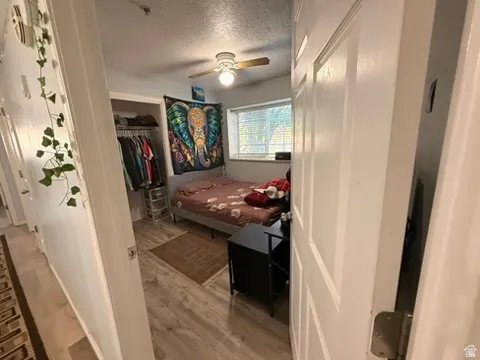 Bedroom featuring wood-finish flooring, a window with blinds, and a ceiling fan with light fixture