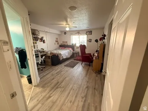 Spacious room featuring wood-finish flooring, a window offering natural light, and a ceiling fan
