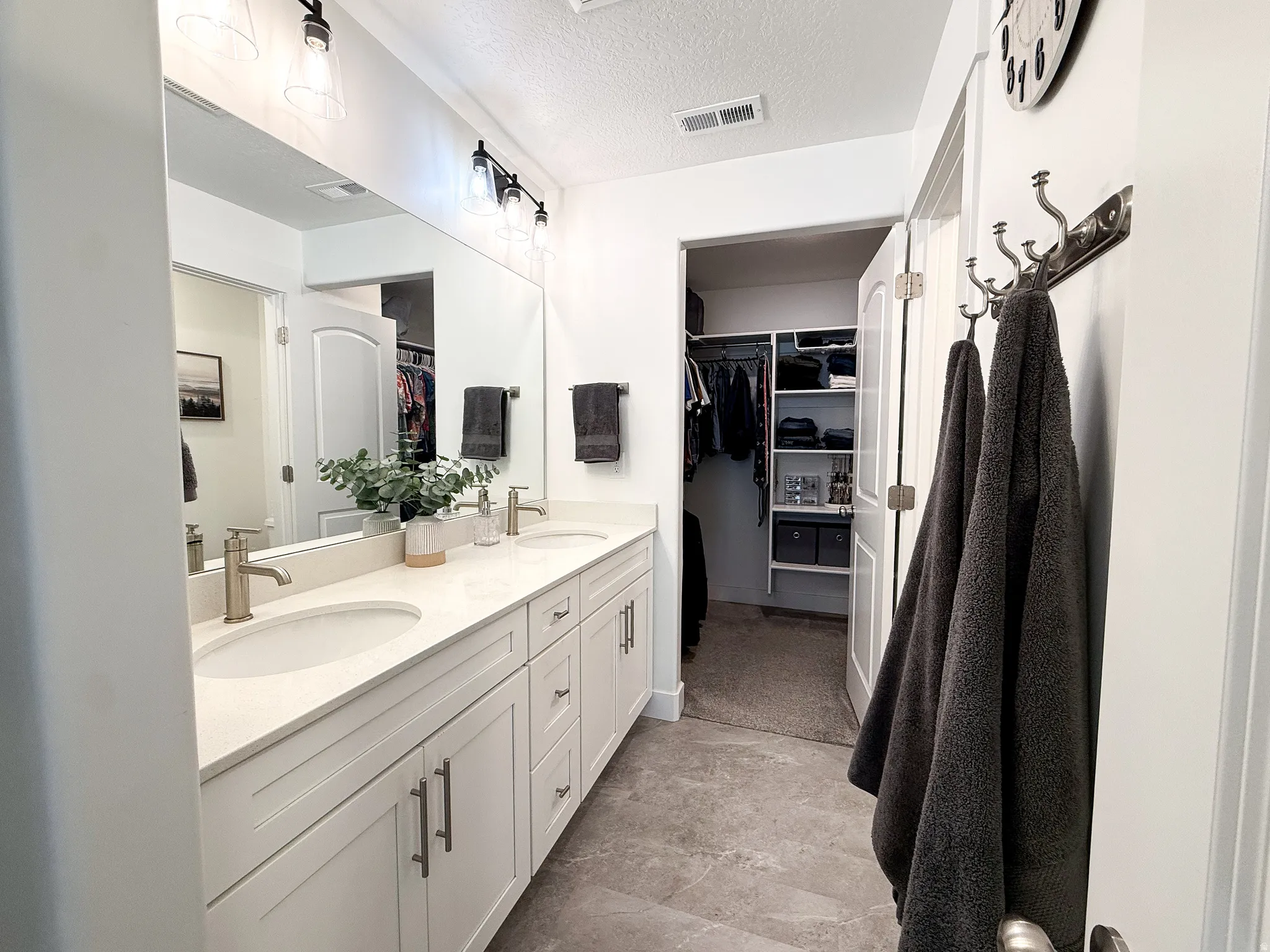 Double vanity with white cabinetry, integrated sinks, brushed nickel faucets, and a full-width mirror