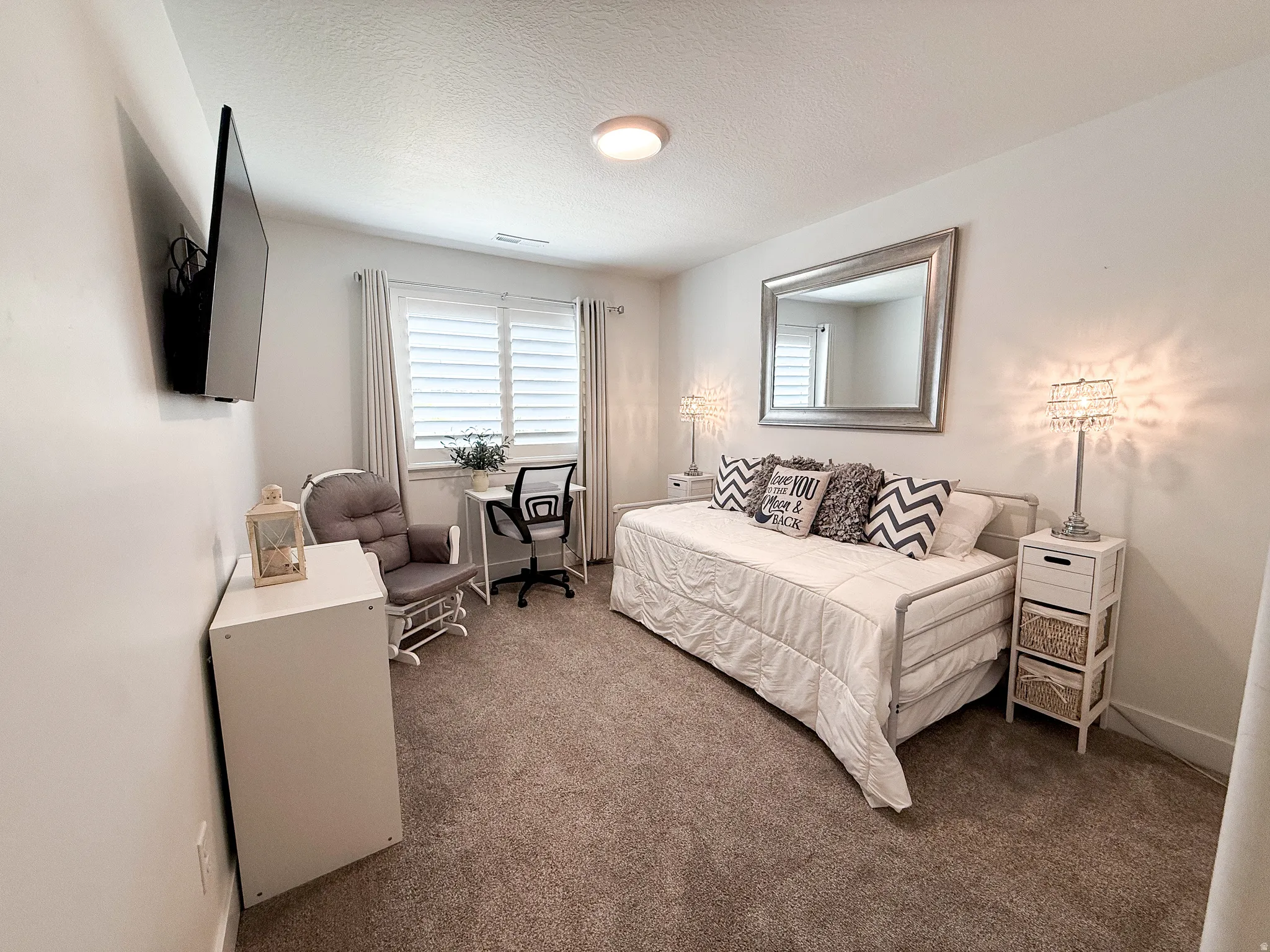 Carpeted room featuring white walls, a single window with white shutters, a flush-mount ceiling light, and a wall-mounted television
