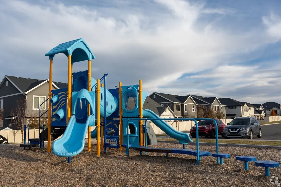 Community playground featuring multiple slides, tunnels, and climbing elements set on a wood chip surface