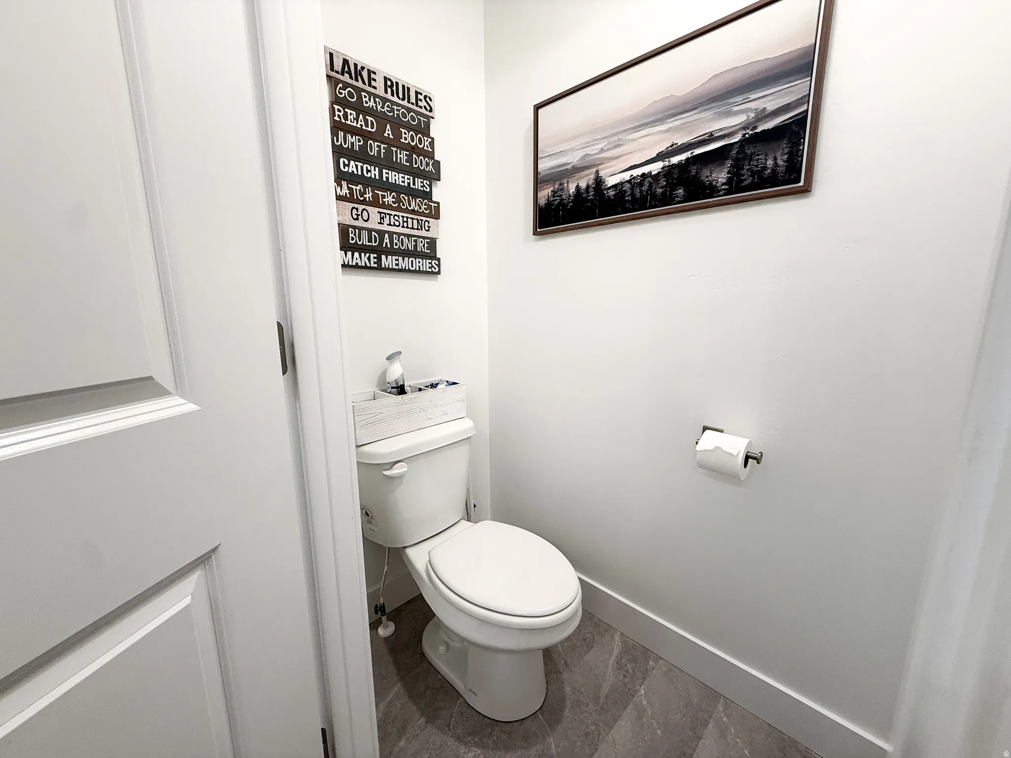 Compact powder room featuring a contemporary white toilet, grey tile flooring, and crisp white walls