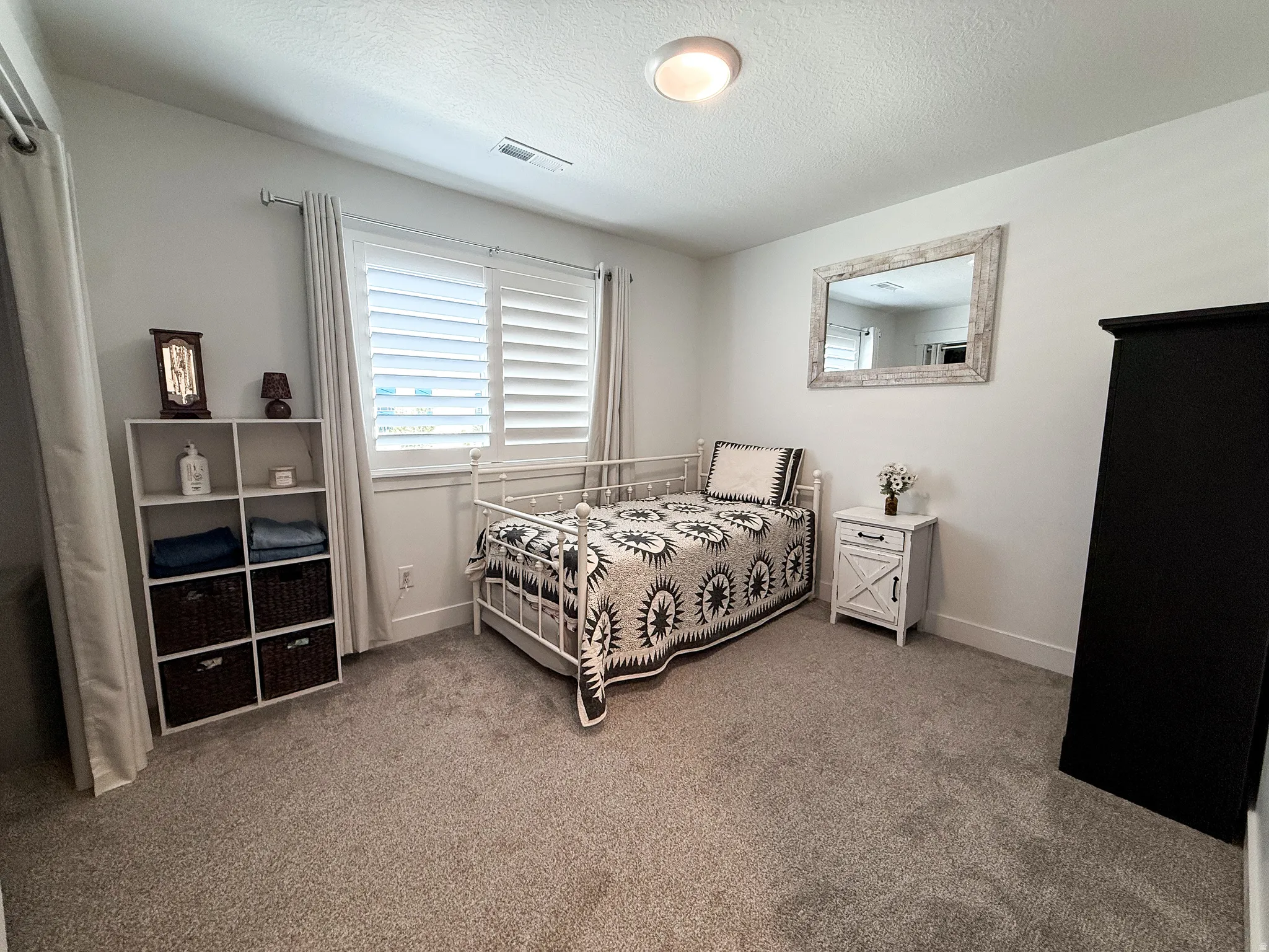 Bright interior space featuring a window with white louvered shutters, recessed lighting, and light-toned carpeting