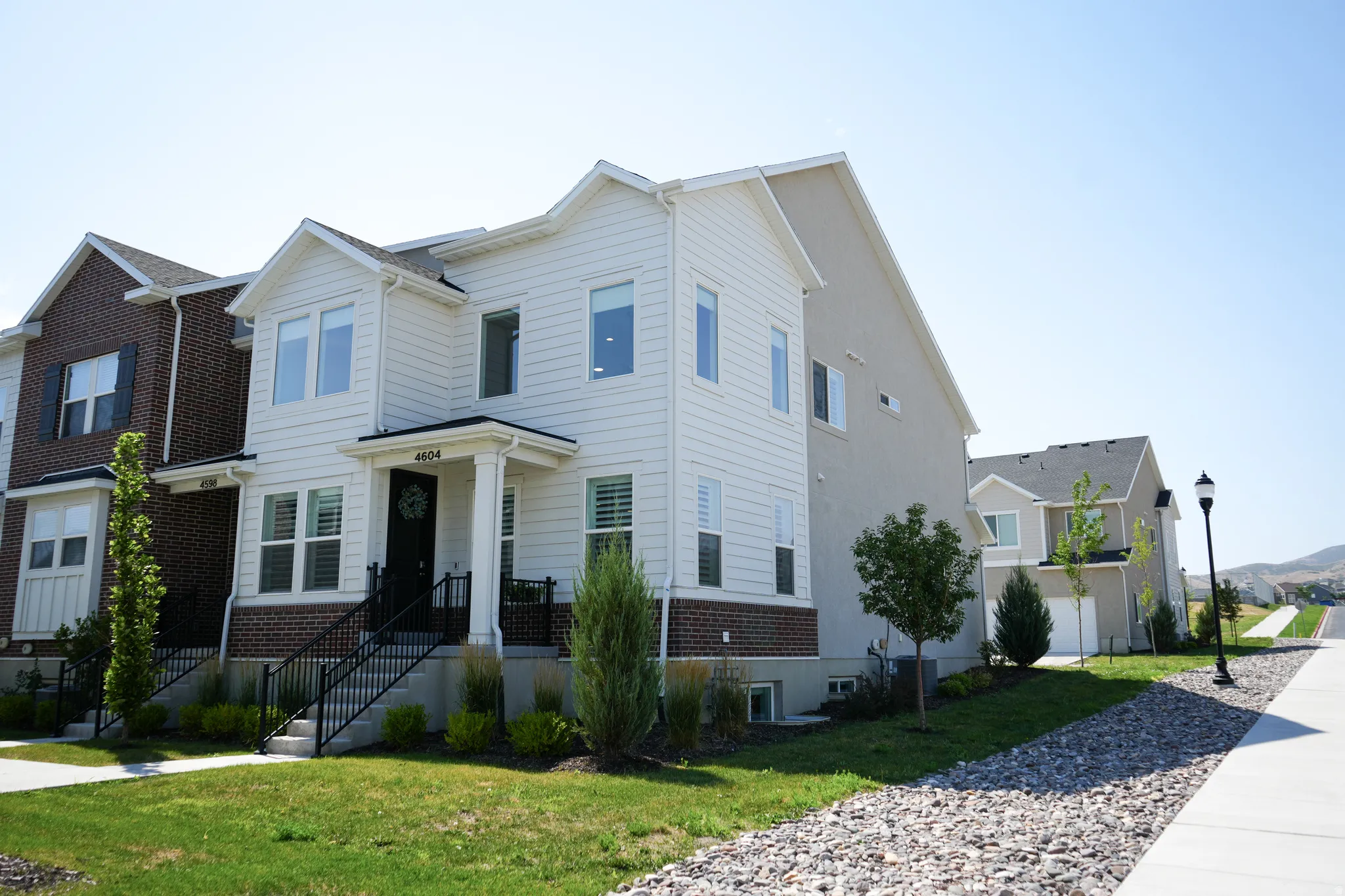 Contemporary townhome featuring white siding and brick accents