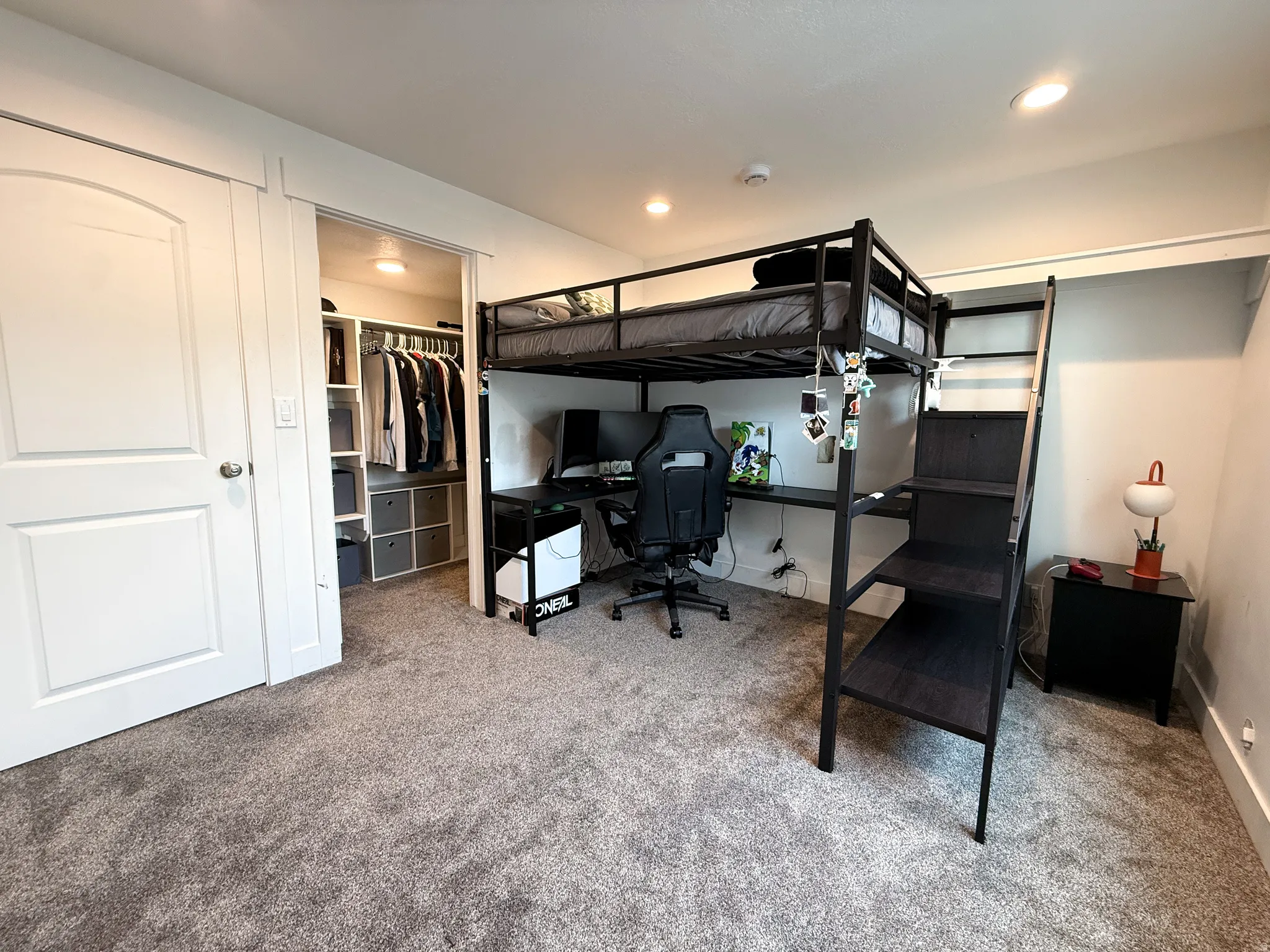 Carpeted room featuring a built-in closet with shelving and hanging rods