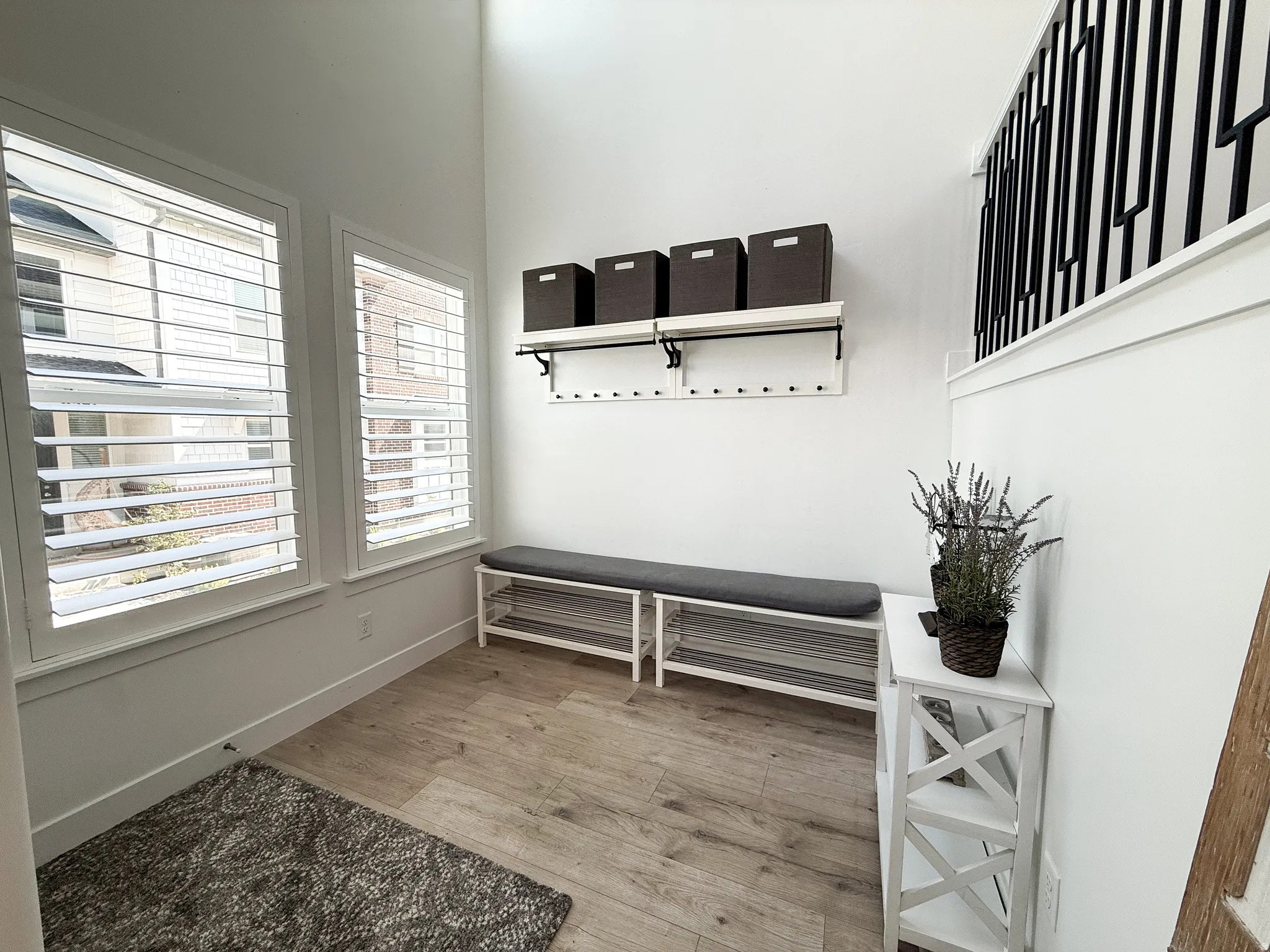 Entryway featuring two windows with plantation shutters, wood-finish flooring, and a white accent wall