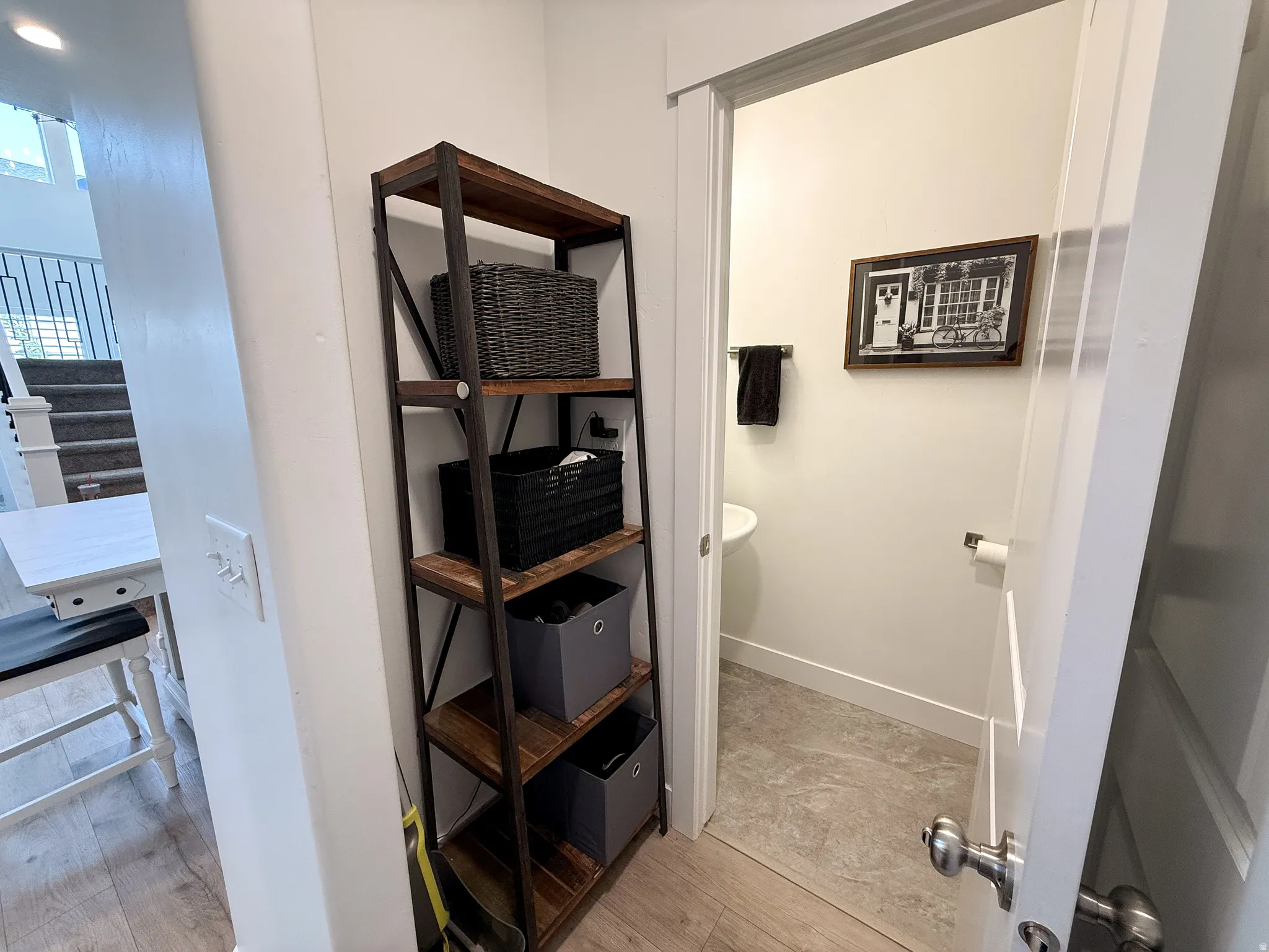 Compact powder room featuring a wall-mounted sink, tile flooring, and white trim