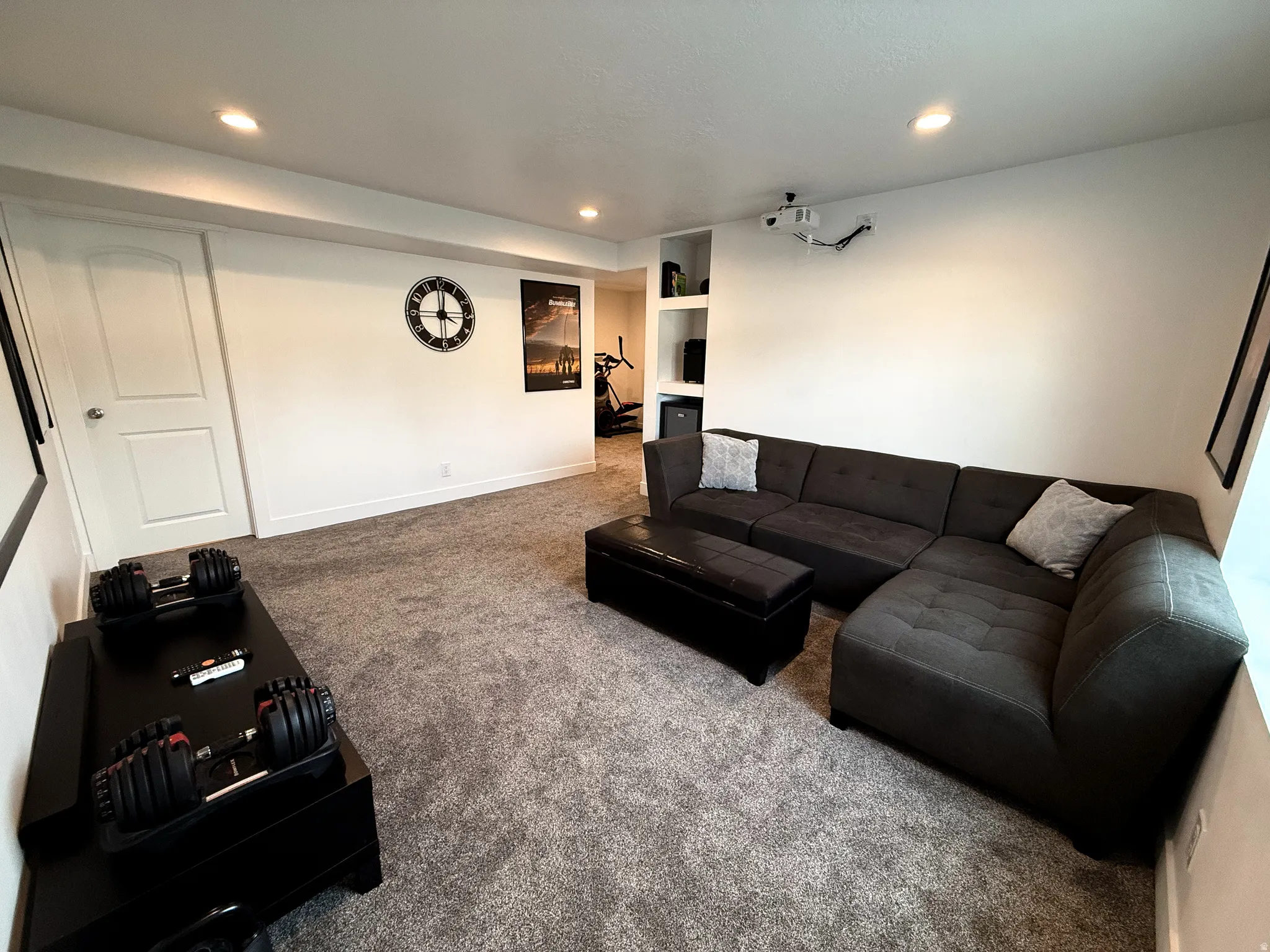 Carpeted interior space featuring recessed lighting, white walls, built-in shelving, and a white interior door
