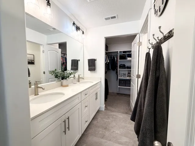 Double vanity with white cabinetry, integrated sinks, brushed nickel faucets, and a full-width mirror
