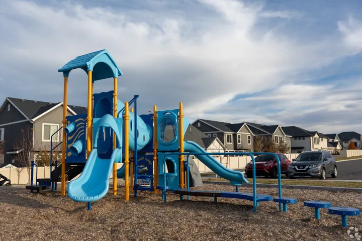 Community playground featuring multiple slides, tunnels, and climbing elements set on a wood chip surface