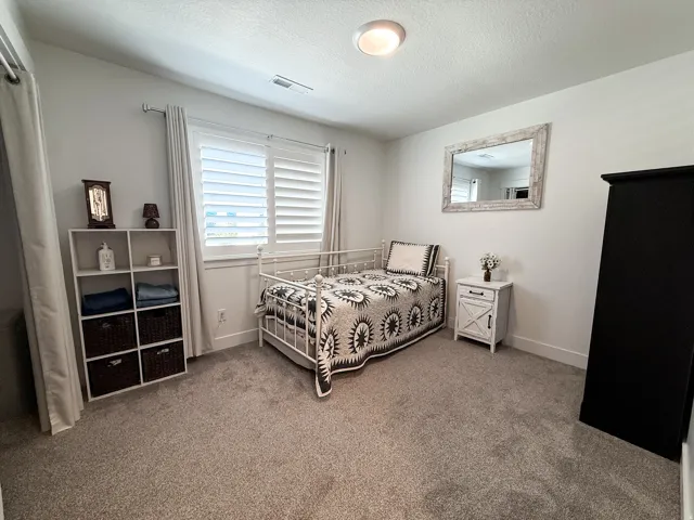 Bright interior space featuring a window with white louvered shutters, recessed lighting, and light-toned carpeting