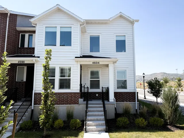 Contemporary townhome facade featuring white siding and brick accents