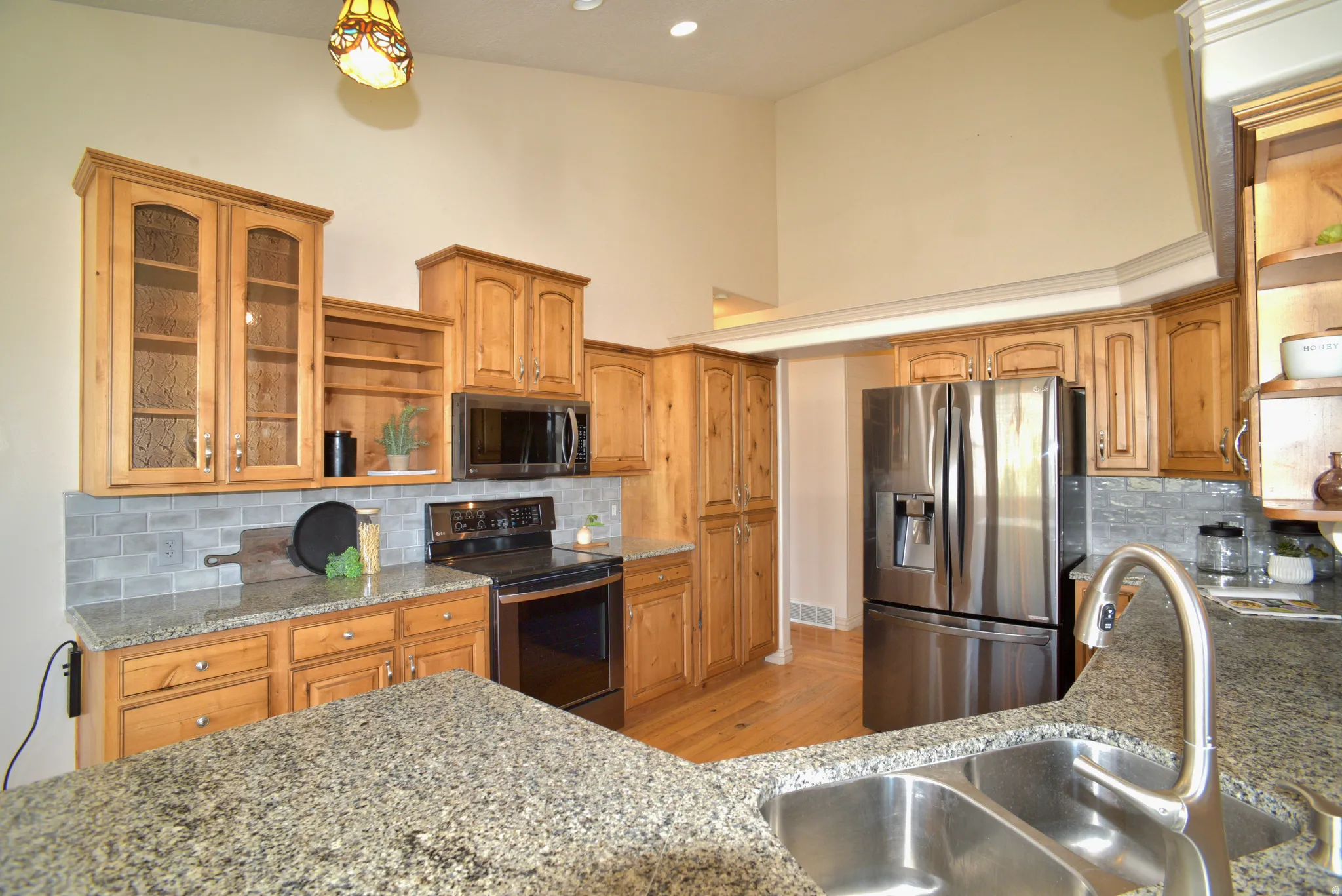 GORGEOUS GRANITE ADORNS LARGE KITCHEN WITH DARK STAINLESS STEEL APPLIANCES, CUSTOM CABINETS AND PANTRY
