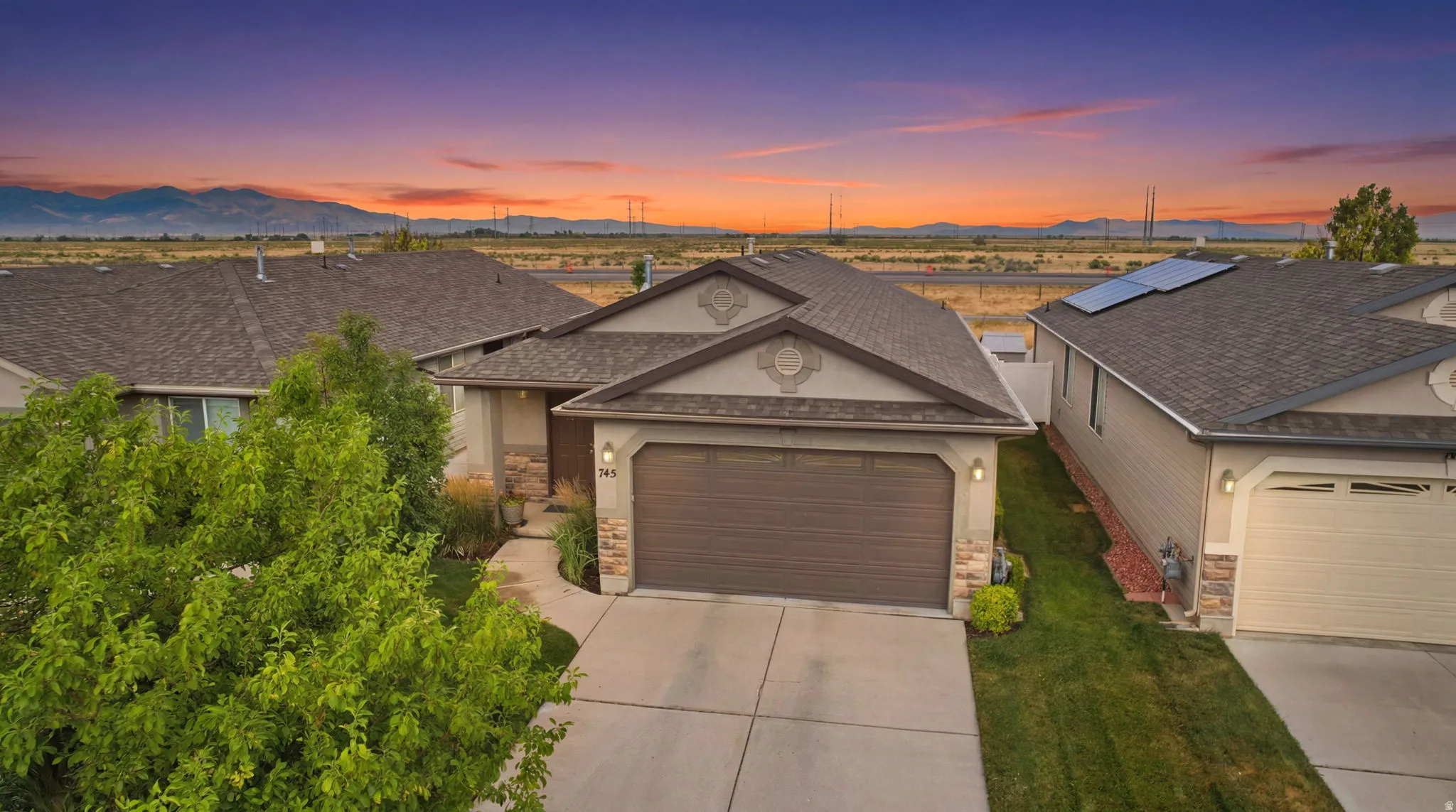 Single-story residence featuring a brown garage door, stone accent facade, and a concrete driveway