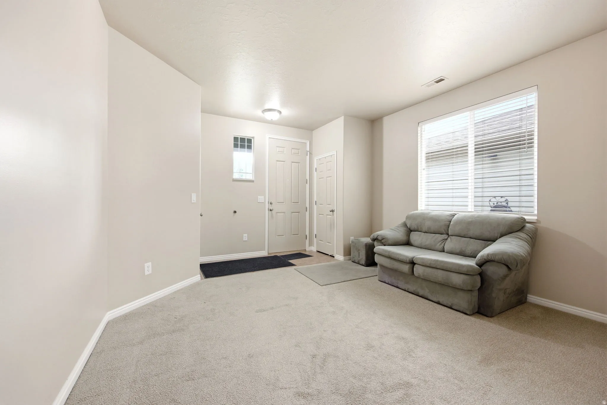 Open living space featuring neutral carpeting and light-toned walls