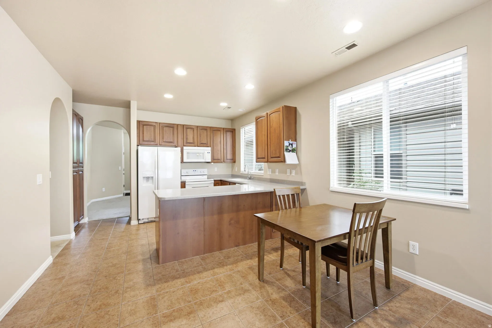 Kitchen featuring wood-finish cabinetry, white appliances, and light-toned countertops