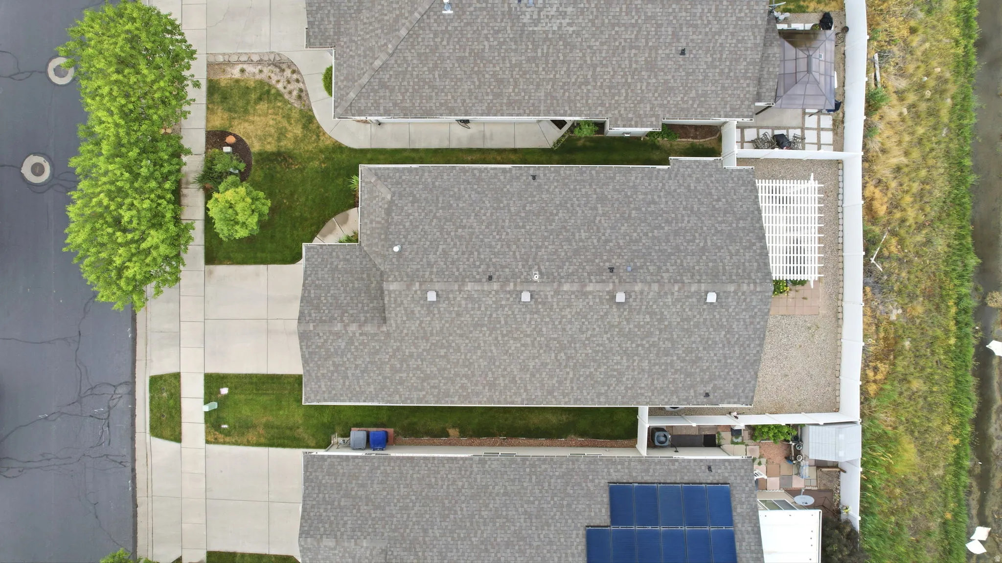 Shingled roofline with a gravel side yard and white pergola